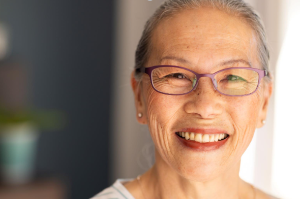 Smiling elderly asian woman wearing glasses, looking at camera indoors